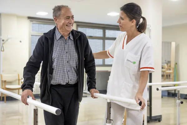 Voluntaria de Domus Vi realizando ejercicios de movilidad con un paciente en situación de dependencia.